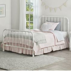 a white bed sitting next to a window on top of a carpeted bedroom floor