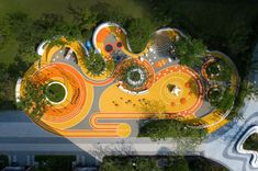 an aerial view of a colorful playground in the middle of a park with lots of trees