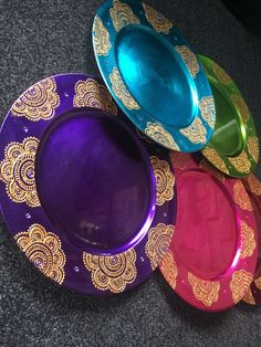 four colorful plates sitting on top of a gray floor next to a black tablecloth