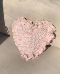 a pink crocheted heart sitting on top of a white couch