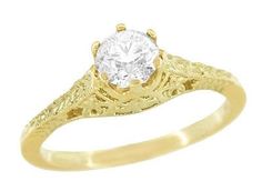 a gold ring with a diamond in the center and filigrees on it