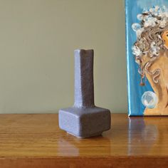 a small gray block sitting on top of a wooden table next to a blue painting