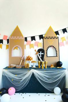 a table topped with cake and balloons in front of a castle wallpapered backdrop