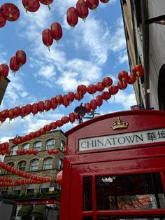 a red phone booth with chinese lanterns hanging from it