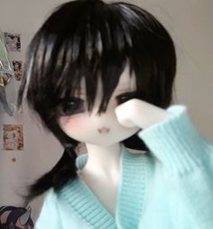 a doll with black hair wearing a blue sweater