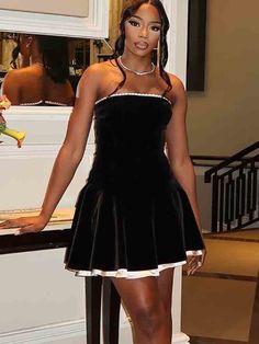 a woman in a short black dress posing for the camera