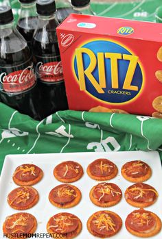 an assortment of snacks and sodas on a green tablecloth next to a box of ritz crackers