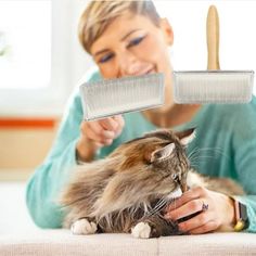 a woman is holding a cat with a grater on it's head and looking at the cat