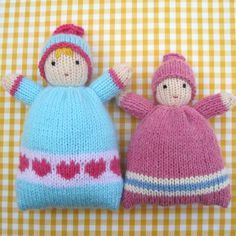 two knitted dolls sitting next to each other on a yellow and white checkered tablecloth