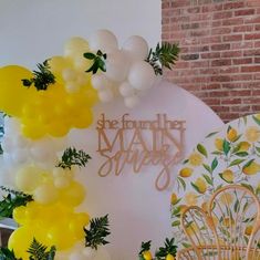 balloons and greenery decorate the backdrop for a lemon themed baby shower at an event