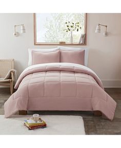 a bed with pink comforter and pillows