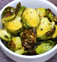 a white bowl filled with brussel sprouts on top of a wooden table