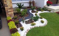 a garden with rocks and plants in front of a house