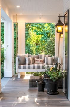 a porch with potted plants on the floor and hanging lights in the ceiling above it