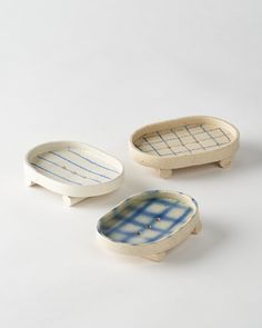 three pieces of pottery sitting on top of a white table