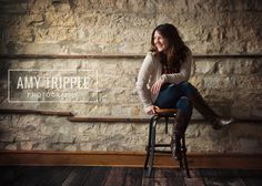 a woman sitting on top of a wooden stool in front of a stone wall with the words any trippie photography