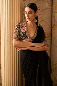 Elevate your style with this exquisite black raw silk embroidered blouse featuring stunning mirror embellishments. Paired with a chiffon drape sari adorned with an organza ruffle, this ensemble exudes sophistication and timeless beauty, making it perfect for special occasions and celebrations. Black Saree Blouse Designs, Drape Sari, Black Saree Blouse, Black Blouse Designs, Saree Chiffon, Ridhi Mehra, Organza Blouse, Plain Saree, Indian Saree Blouse