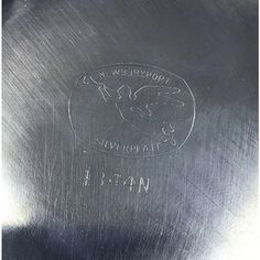 a close up of a metal object with writing on it's side and an image of a bird in the middle