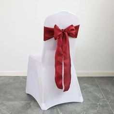 a white chair with a red bow tied to it's back on a tile floor