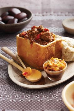 an assortment of food on a plate with bowls and spoons next to it,