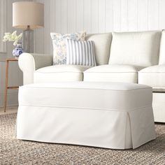 a white couch and ottoman in a living room with pillows on the back of it