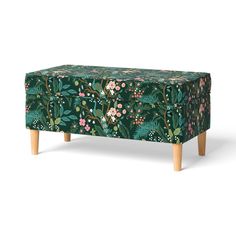 an upholstered foot stool with flowers and leaves on green fabric, against a white background