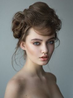 a woman with blue eyes is posing for the camera and has her hair in a bun