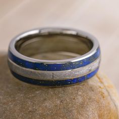 a blue and silver ring sitting on top of a rock