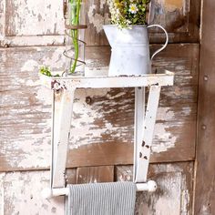 an old white chair with flowers and a towel hanging from it's back rack