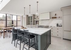 a large kitchen with marble counter tops and bar stools