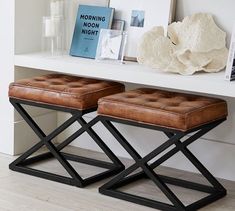 two leather stools sitting on top of a white shelf