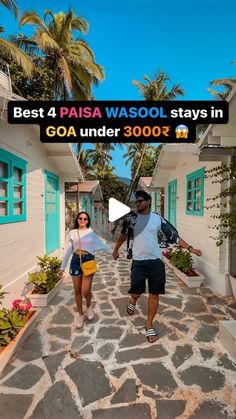 a man and woman walking down a cobblestone road in front of small houses