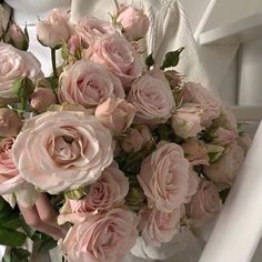 a bouquet of pink roses sitting on top of a white chair