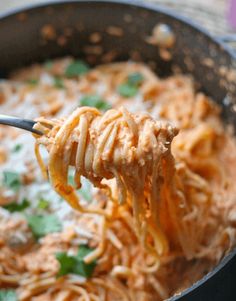 a spoon full of spaghetti being lifted from a skillet