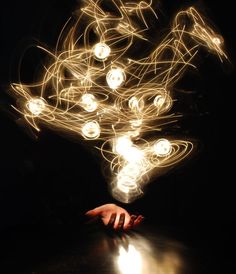 a person's hand reaching for something with lights in the air behind them on a table