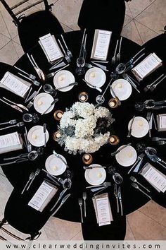 an overhead view of a black table with white flowers and place settings on the tables