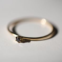 a gold ring with a black diamond sits on a white surface, ready to be worn