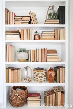 a white book shelf filled with lots of books and vases on top of it