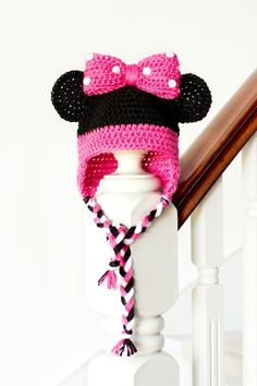 a pink and black knitted minnie mouse hat on top of a white banister