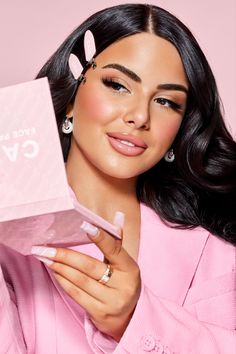 a woman holding up a pink box with the word love on it and an earring