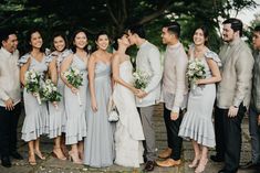 a group of people standing next to each other in front of trees and flowers on the ground