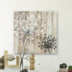 a white table topped with a vase filled with flowers next to a painting on the wall