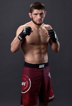 a shirtless man with boxing gloves on posing for a photo in front of a gray background