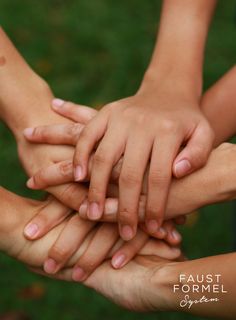 several children's hands stacked on top of each other in the middle of a circle