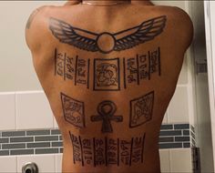 the back of a man's tattoo with symbols on his body and an egyptian key