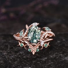 a ring with green and white stones on it sitting on a rock in front of a black background