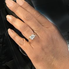 a woman's hand with a diamond ring on top of her finger, in front of a car door