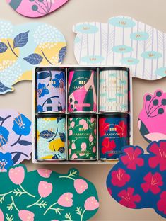 an assortment of colorful tins in a box on a table with paper cut outs