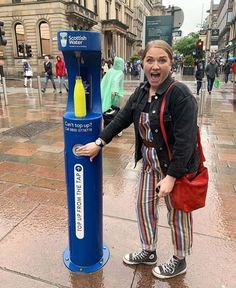 a woman standing next to a blue water fountain