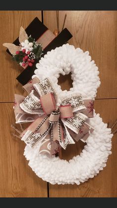 a white wreath with bows on it sitting on the floor next to a black box